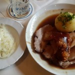 a plate with a dumpling and roast pork next to a plate with Sauerkraut