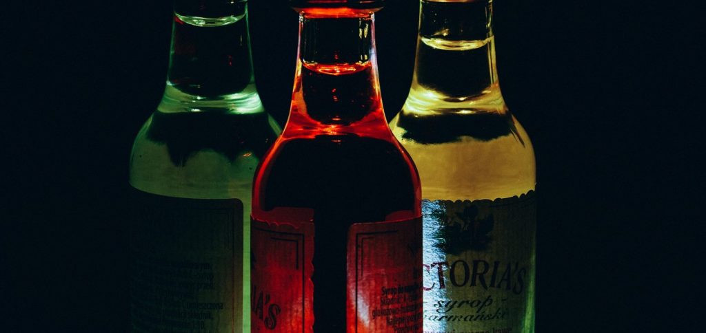 Thee illuminated bottles on a dark background