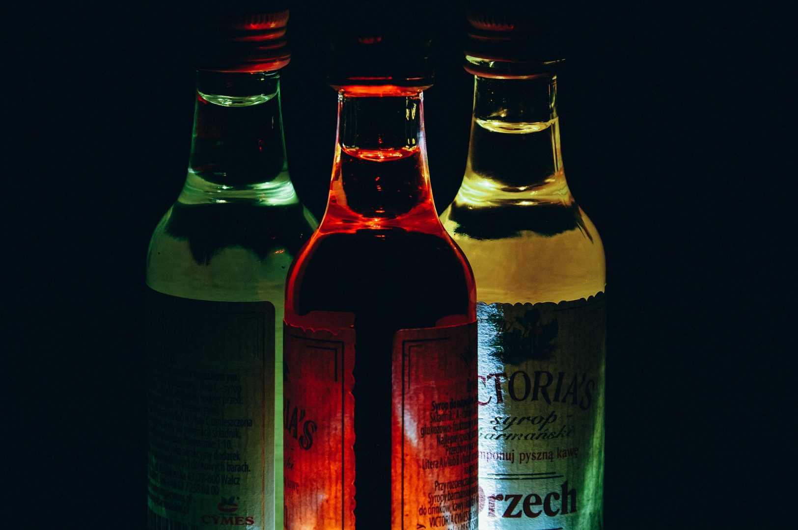 Thee illuminated bottles on a dark background