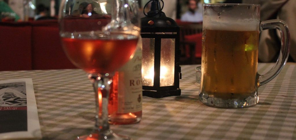 A table with a glas of wine and a beer on it