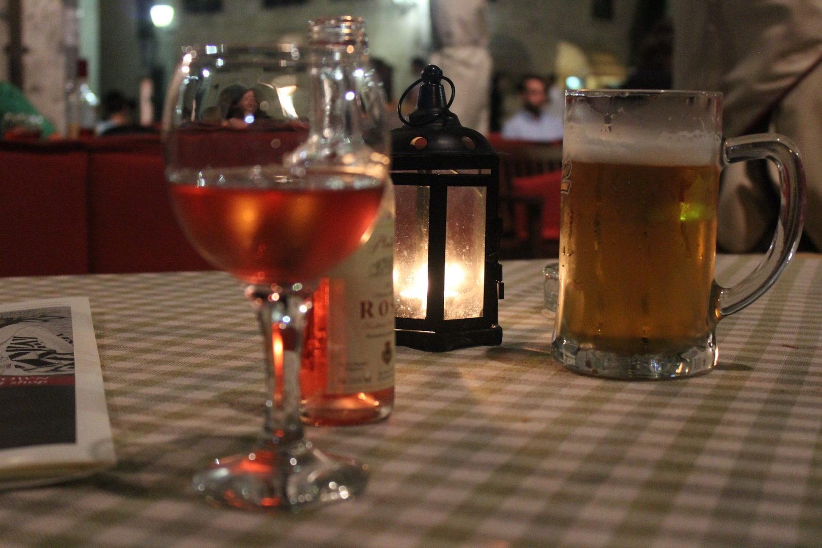 A table with a glas of wine and a beer on it