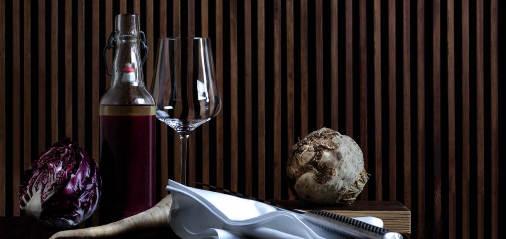 A wine glas and a bottle on a table