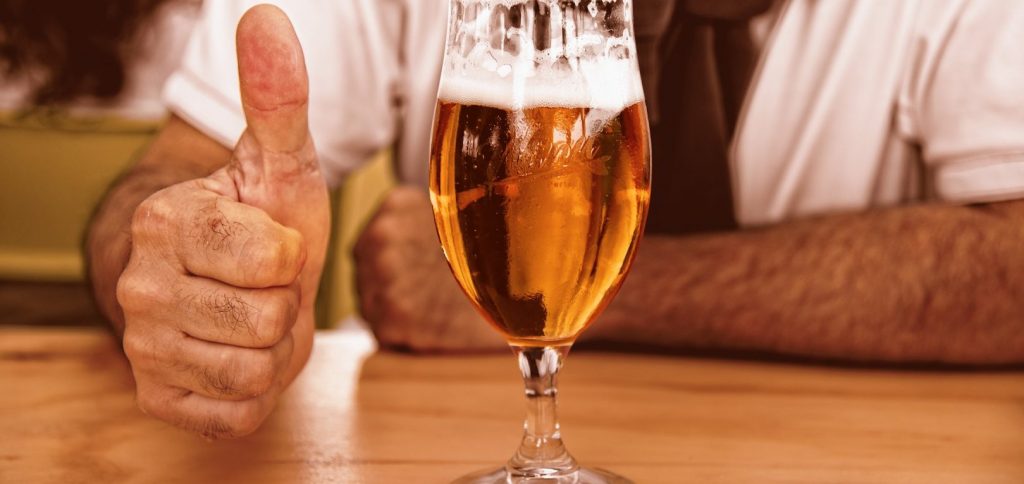 Ein Bier und eine hand, die "Daumen hoch" zeigt