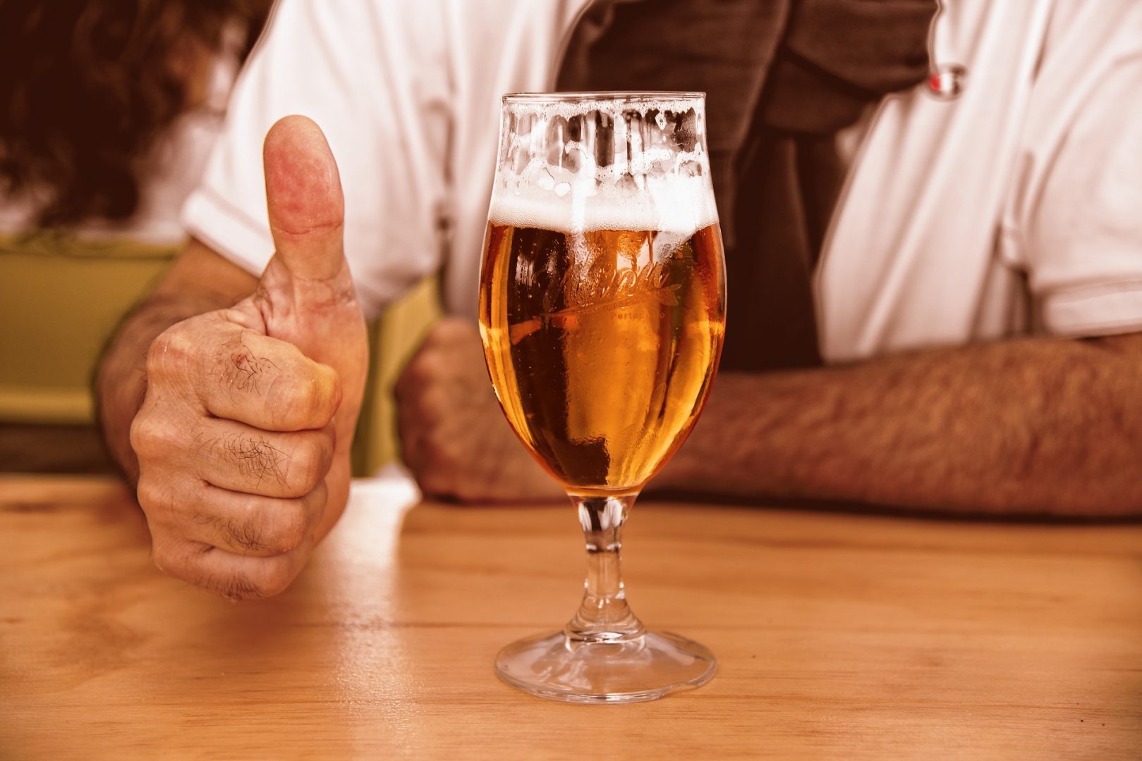 A beer and a hand that's giving thumbs up